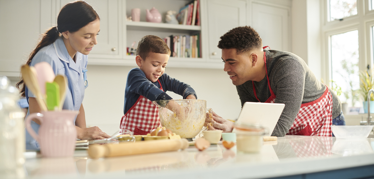 Two parents helping young child mix ingredients in a bowl.