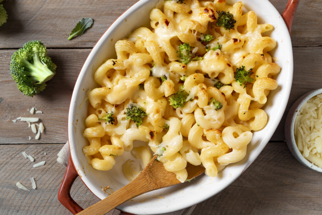Mac and cheese with broccoli and parmesan oven baked, top view. Traditional american meal, creamy macaroni pasta and cheese sauce casserole.