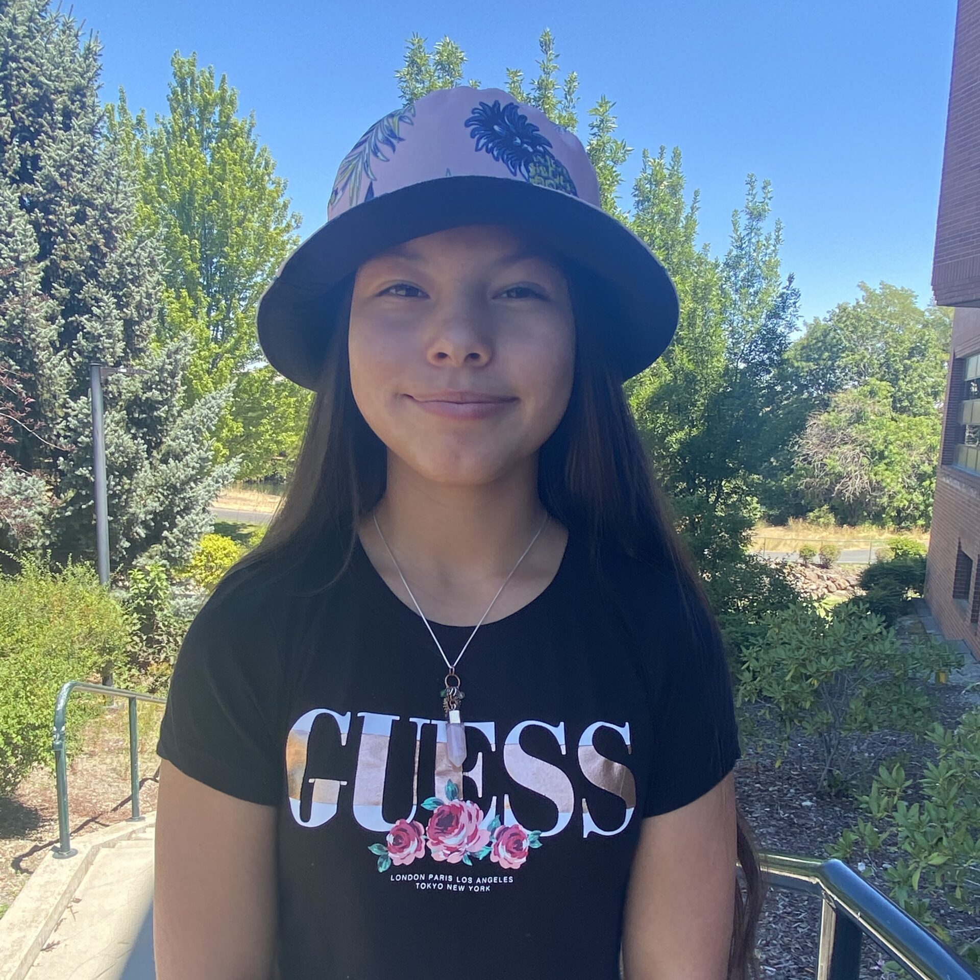 Aurora Whiskeyjack standing outside with blue sky and trees around her.