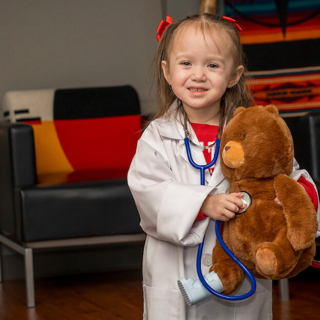 Little bird program participant holding teddy bear posing for the camera