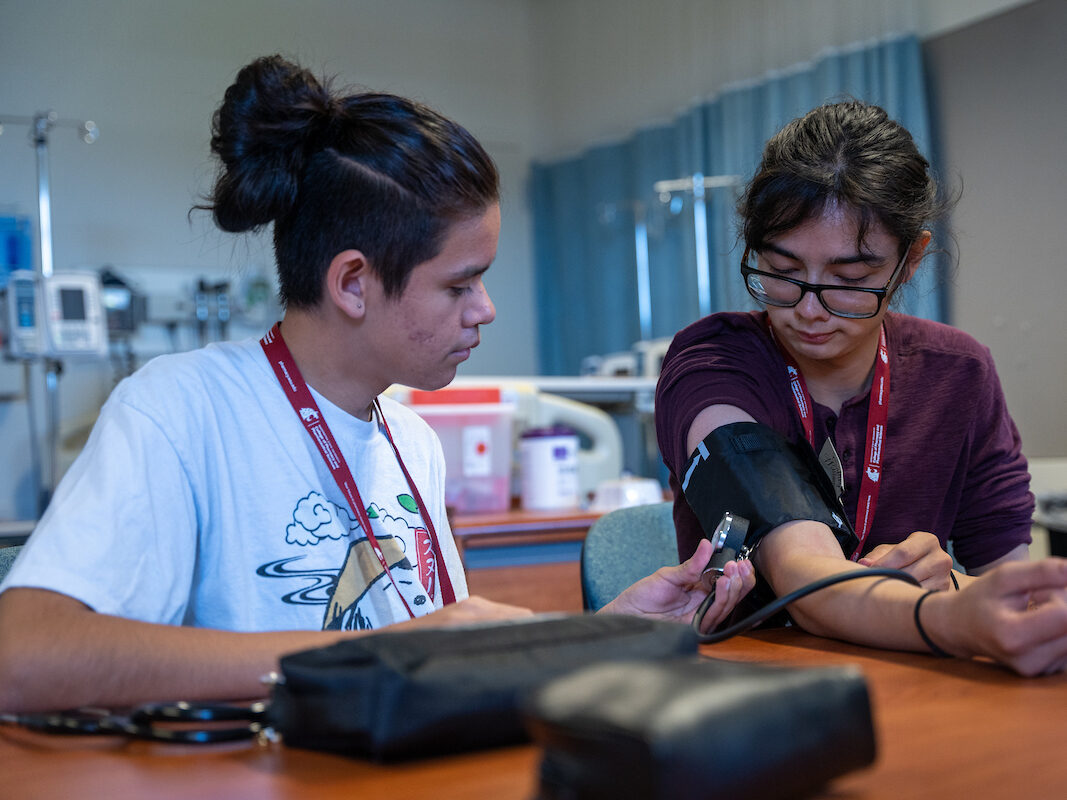 Na-ha-shnee program students working with blood pressure monitor on each other