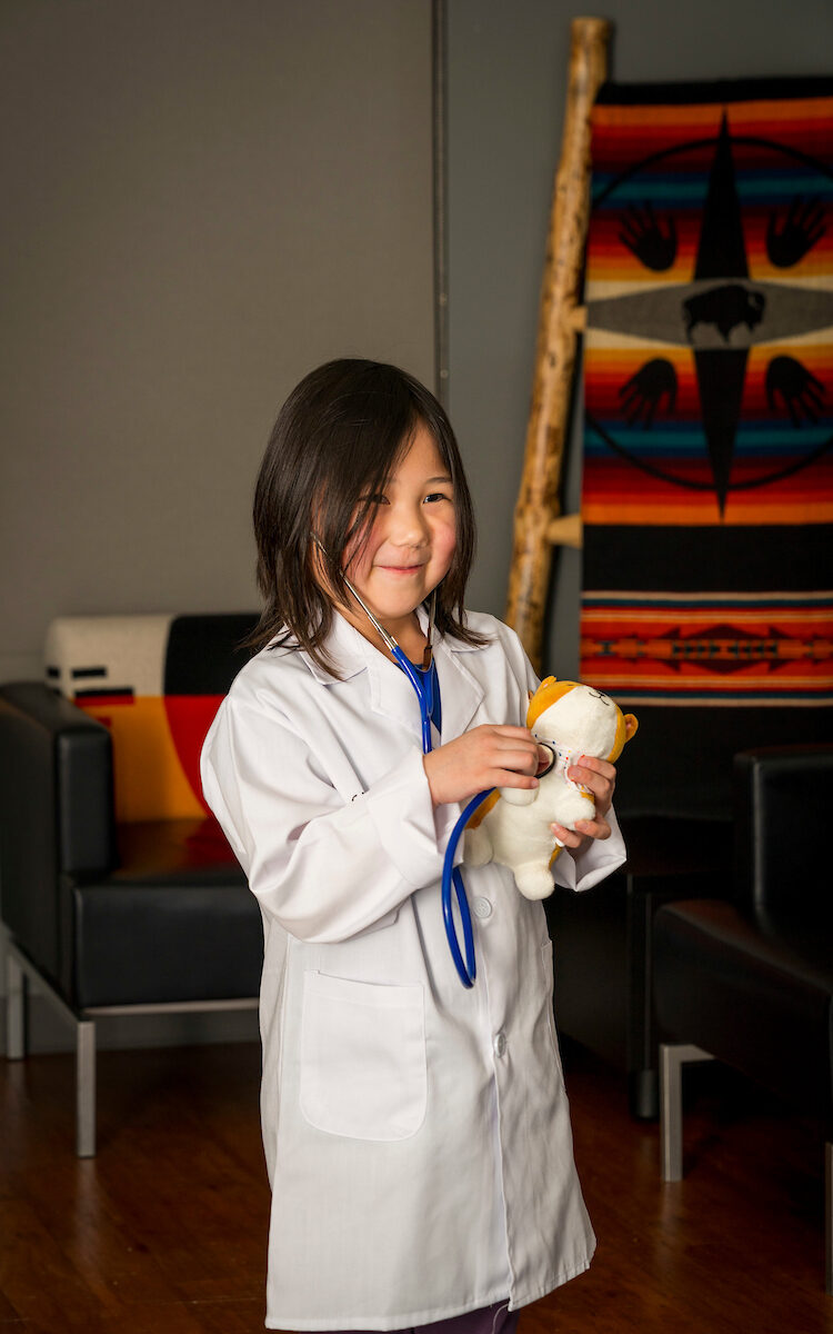 Participant holding teddy bear and putting the stethoscope to its chest. 