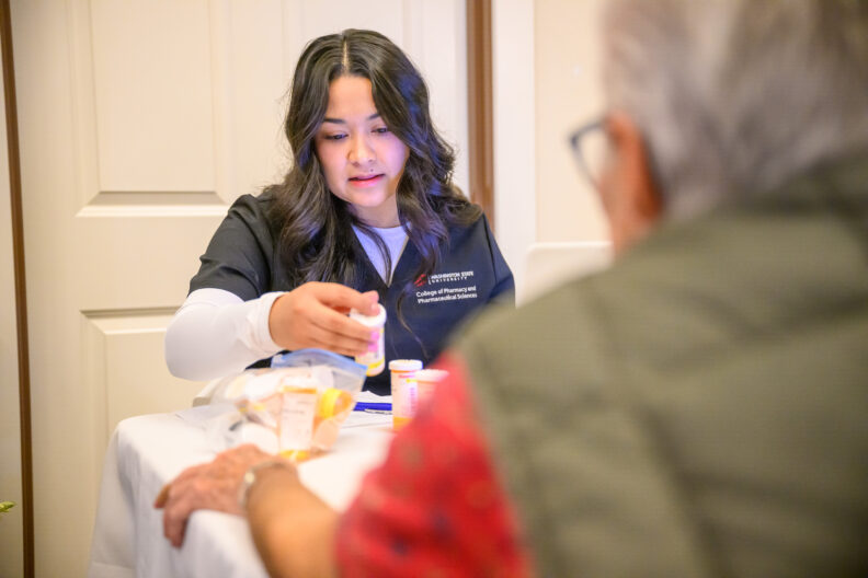 Pharmacy student reviewing multiple pill bottles for older patient.