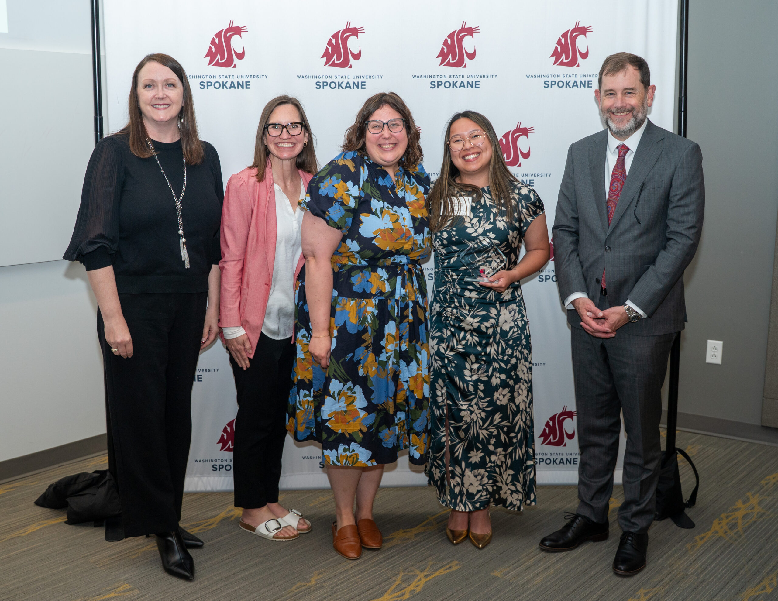 Gillian Freeby holding her Health Sciences Student Leadership Award alongside Interim Dean Julie Akers, Professor Jennifer Robison, Academic and Student Success Advisor Hannah Green, and Provost Chris Riley-Tillman