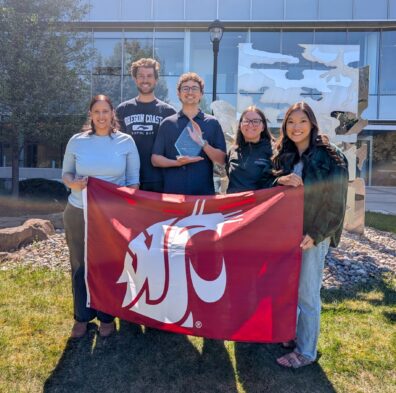 Sports Pharmacy Network at Washington State University posing with their Outstanding Student Chapter Award and the WSU Coug Flag