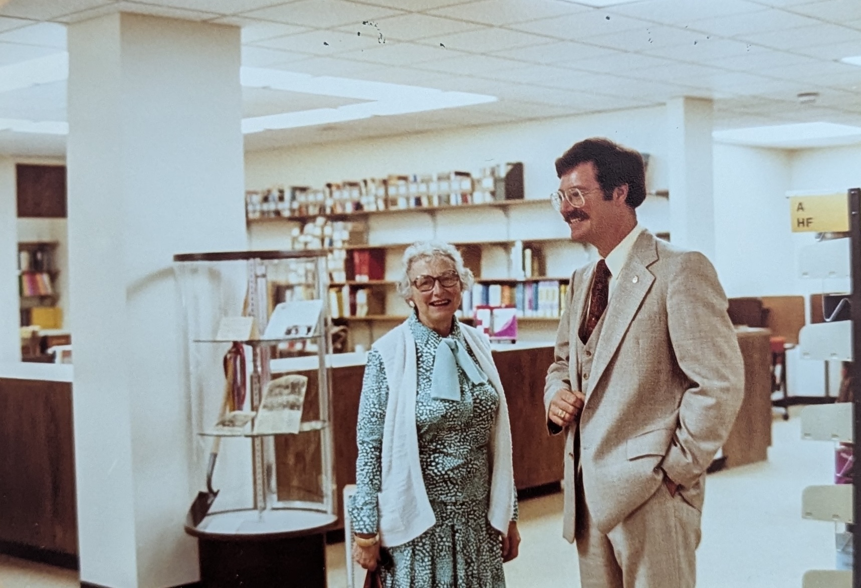 Two older individuals standing in the library