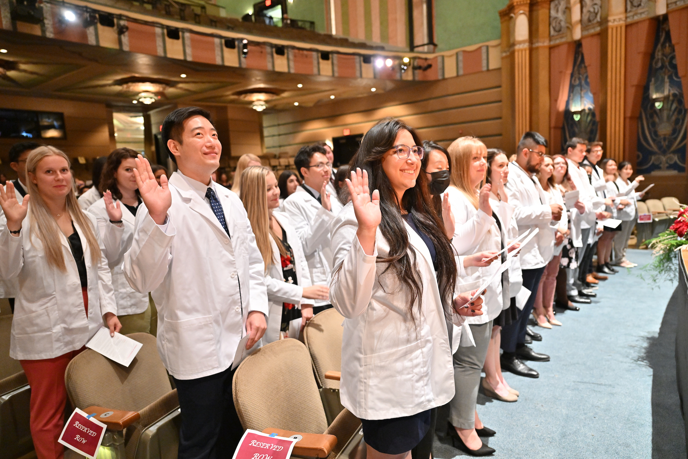 Students with right hands raised participating in graduation ceremony