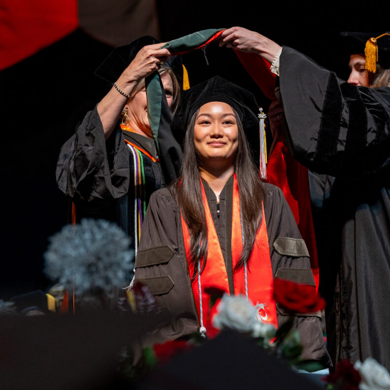 College of pharmacy student being hooded during graduation ceremony