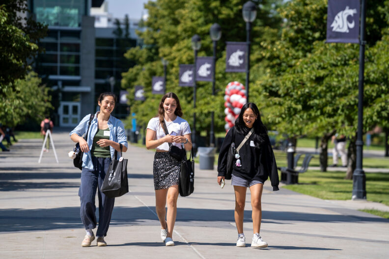 three female students walking on campus during orientation day