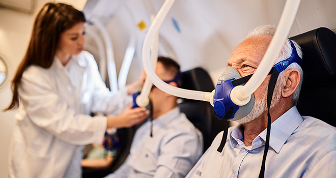 Senior man breathing through mask during oxygen therapy in hyperbaric chamber.