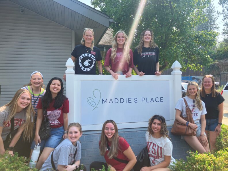 Students pose around the Maddie's Place Sign