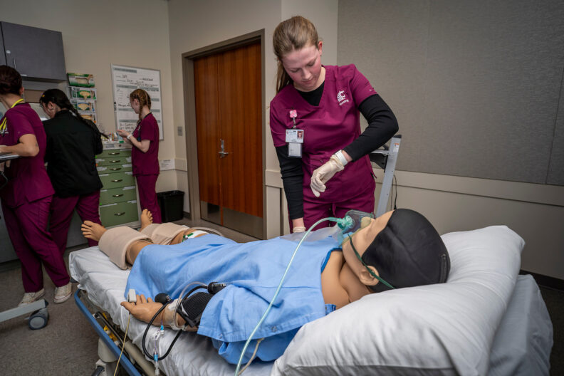 Nursing student with simulation mannequin.