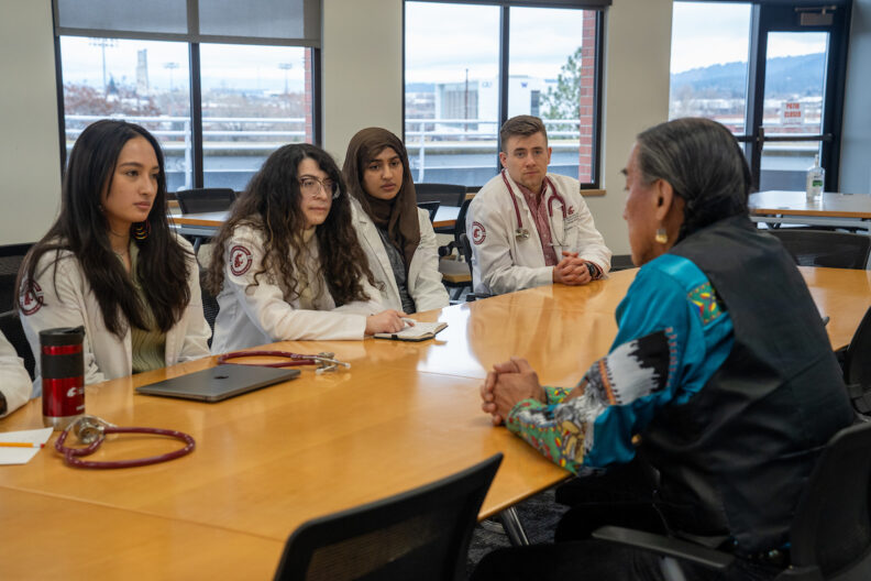 students in white coats listening to speaker