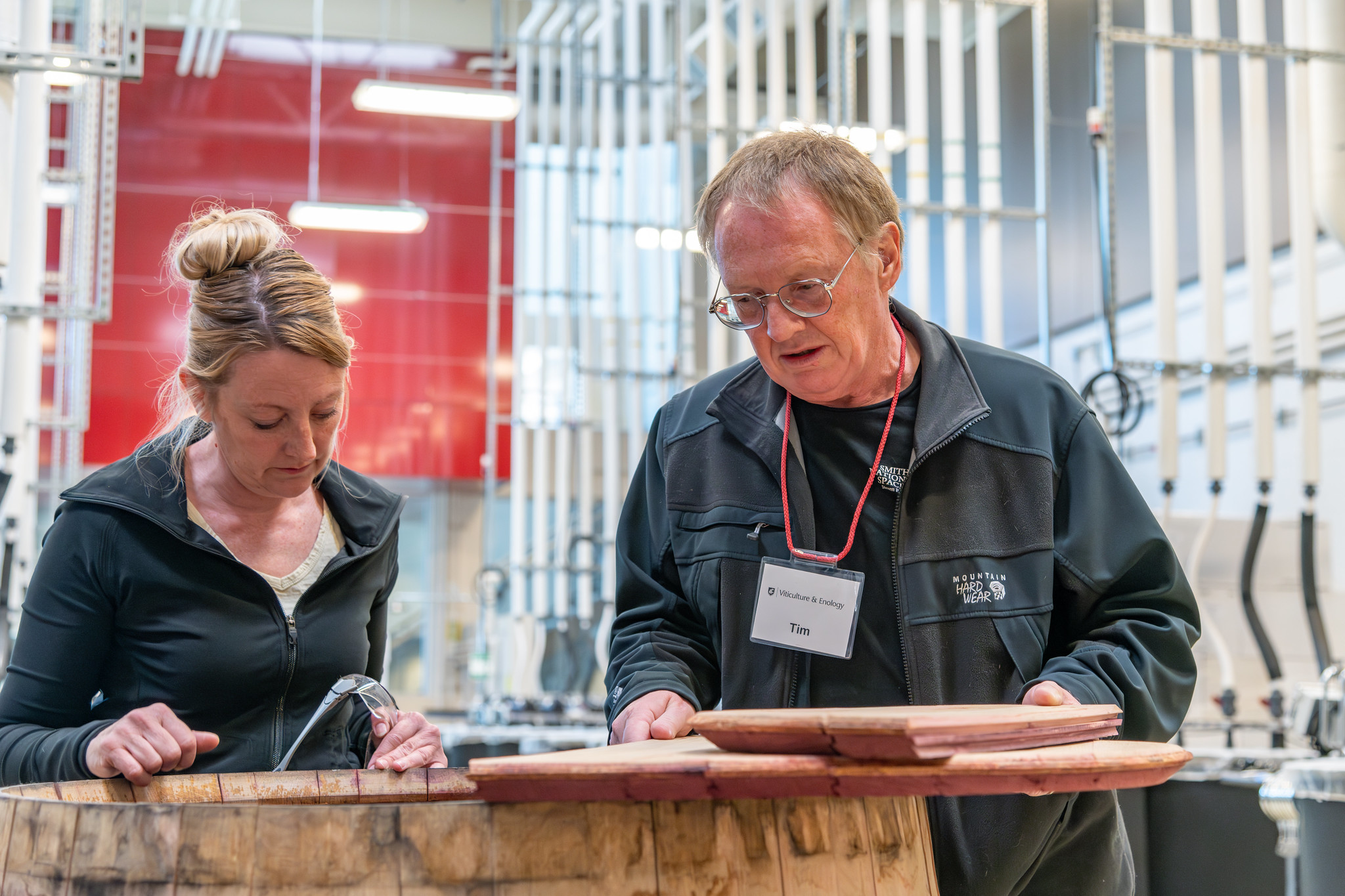 Two students inspecting the inside of a wooden wine barrel in the Wine Science Center.
