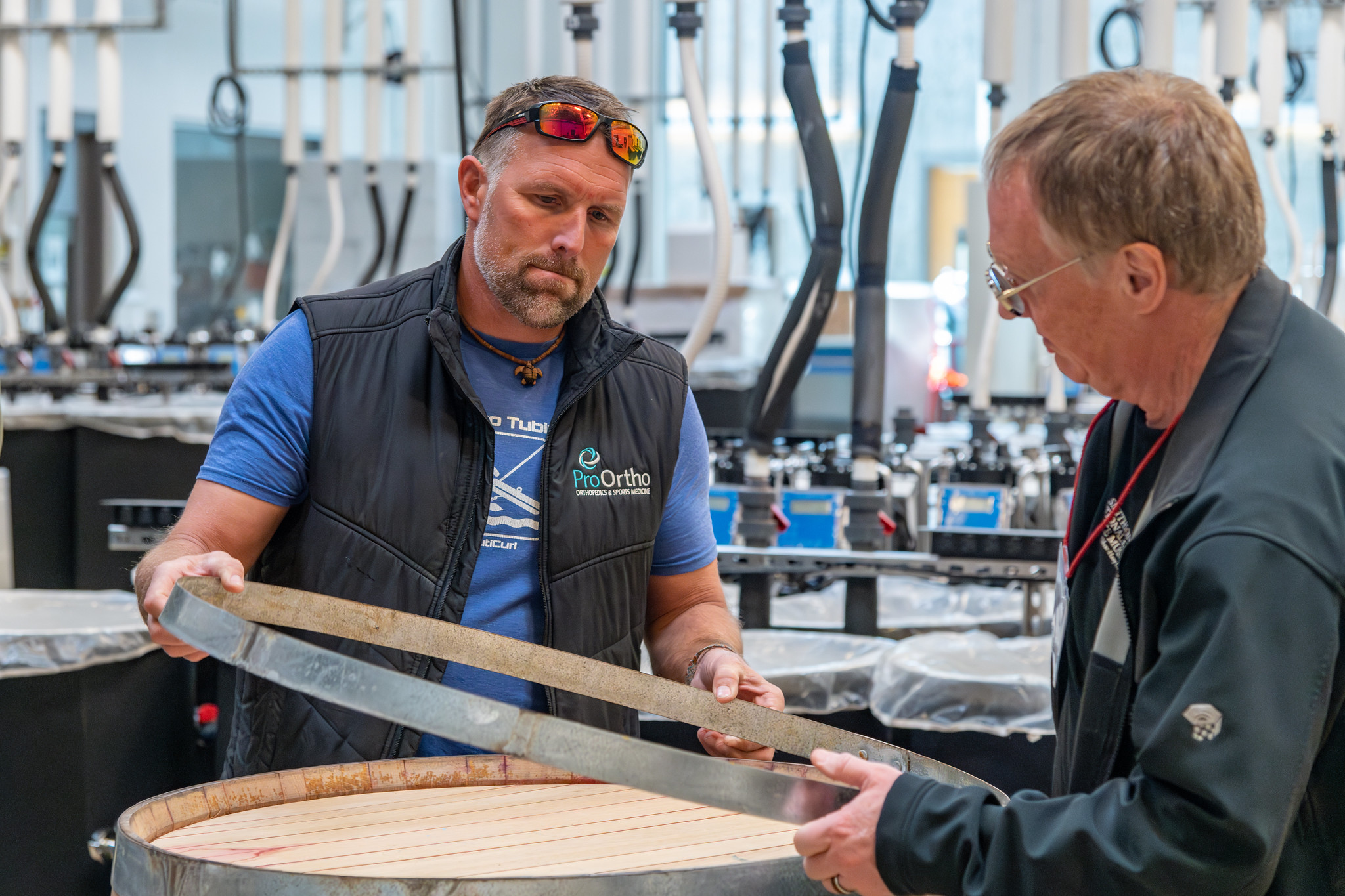 Two students pulling a metal ring off of the top of a wooden wine barrel in the Wine Science Center.