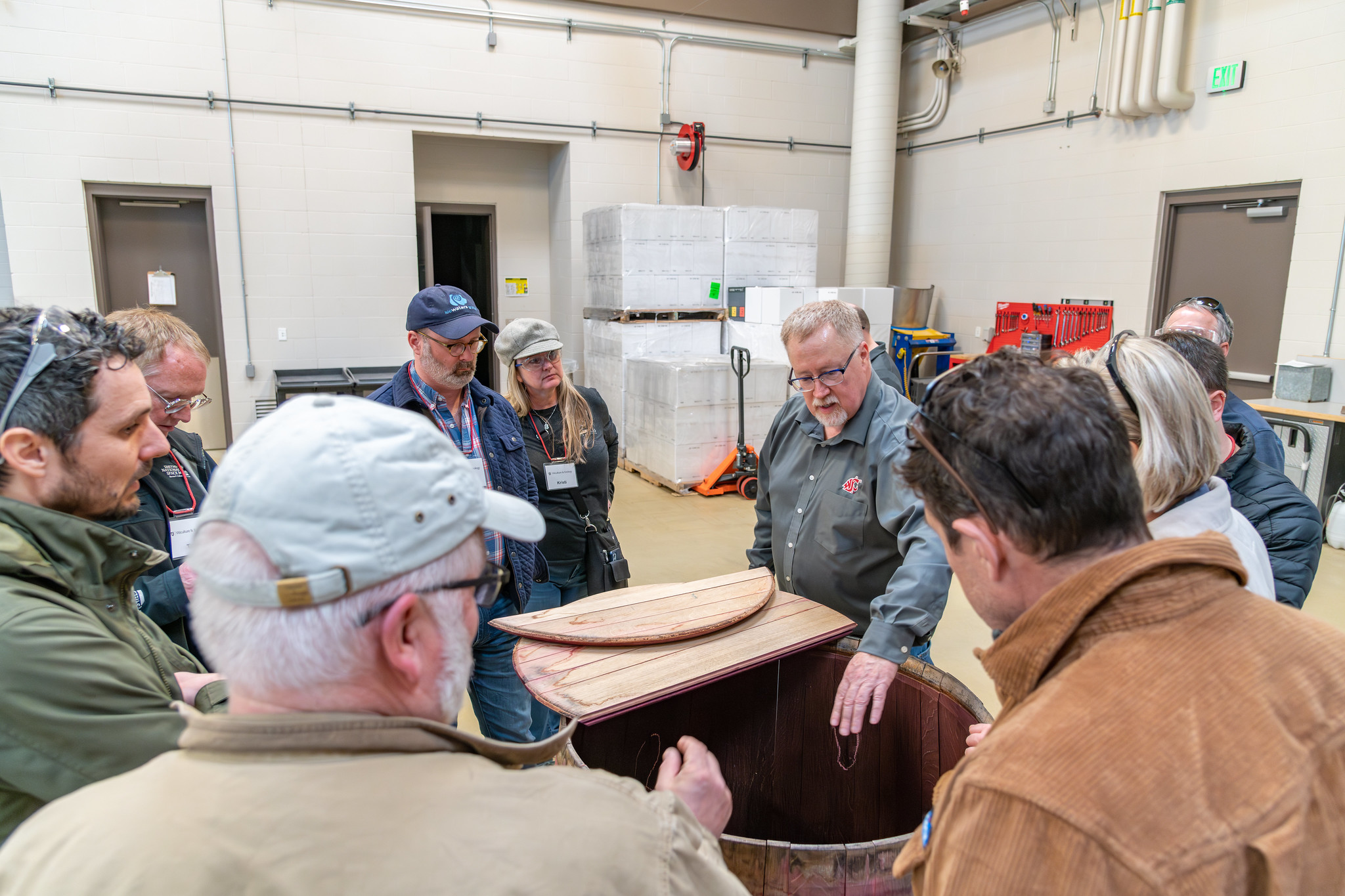 Professor showing a group of students the inside of a wooden wine barrel.
