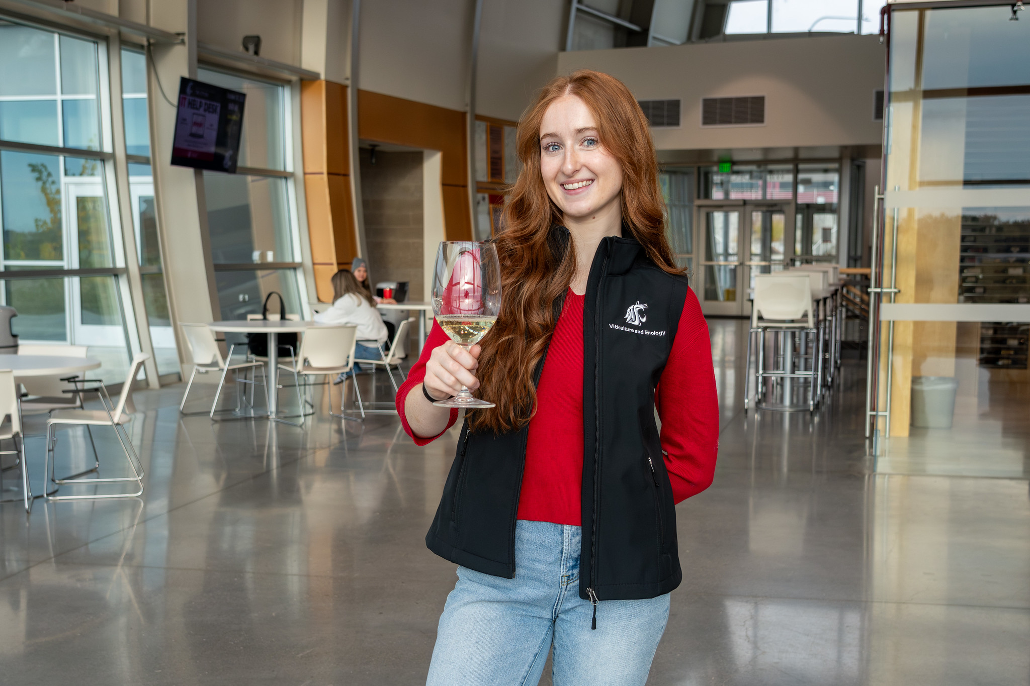 Student wearing a WSU Viticulture & Enology vest holding a wine glass in the WSU Wine Science Center.