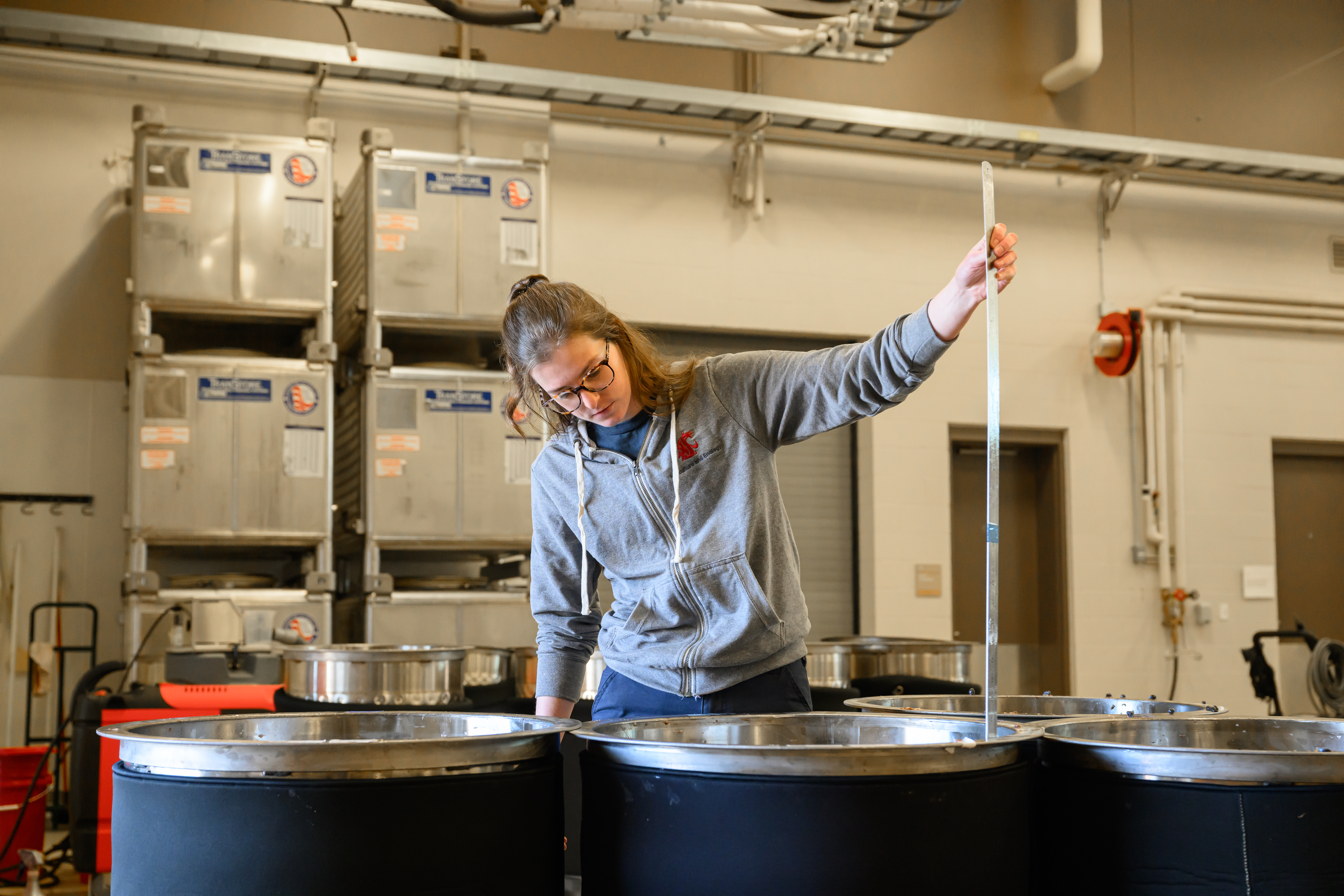 Student examining large metal barrels.