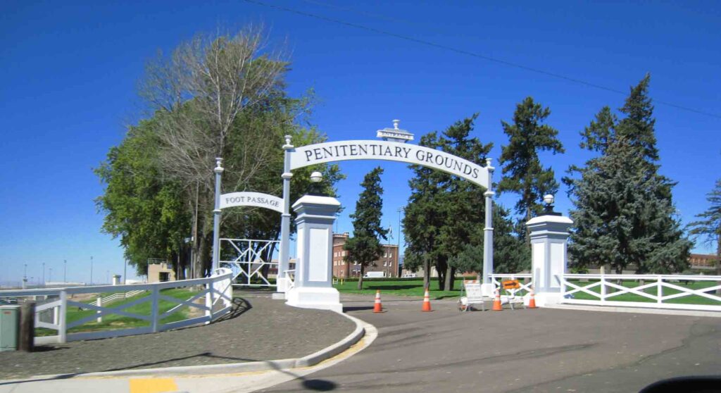 picture of the gated entrance with a sign that says "penitentiary grounds"