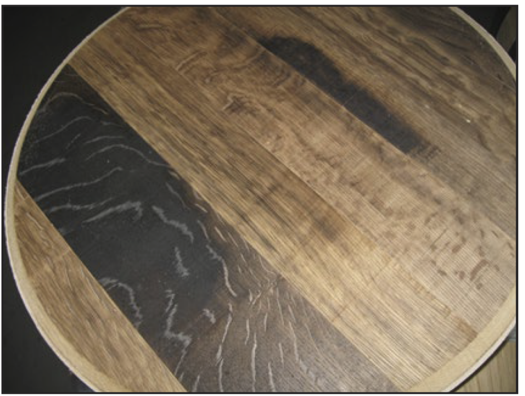 A wine barrel head showing different color staves, where some are light brown, and some are nearly black.