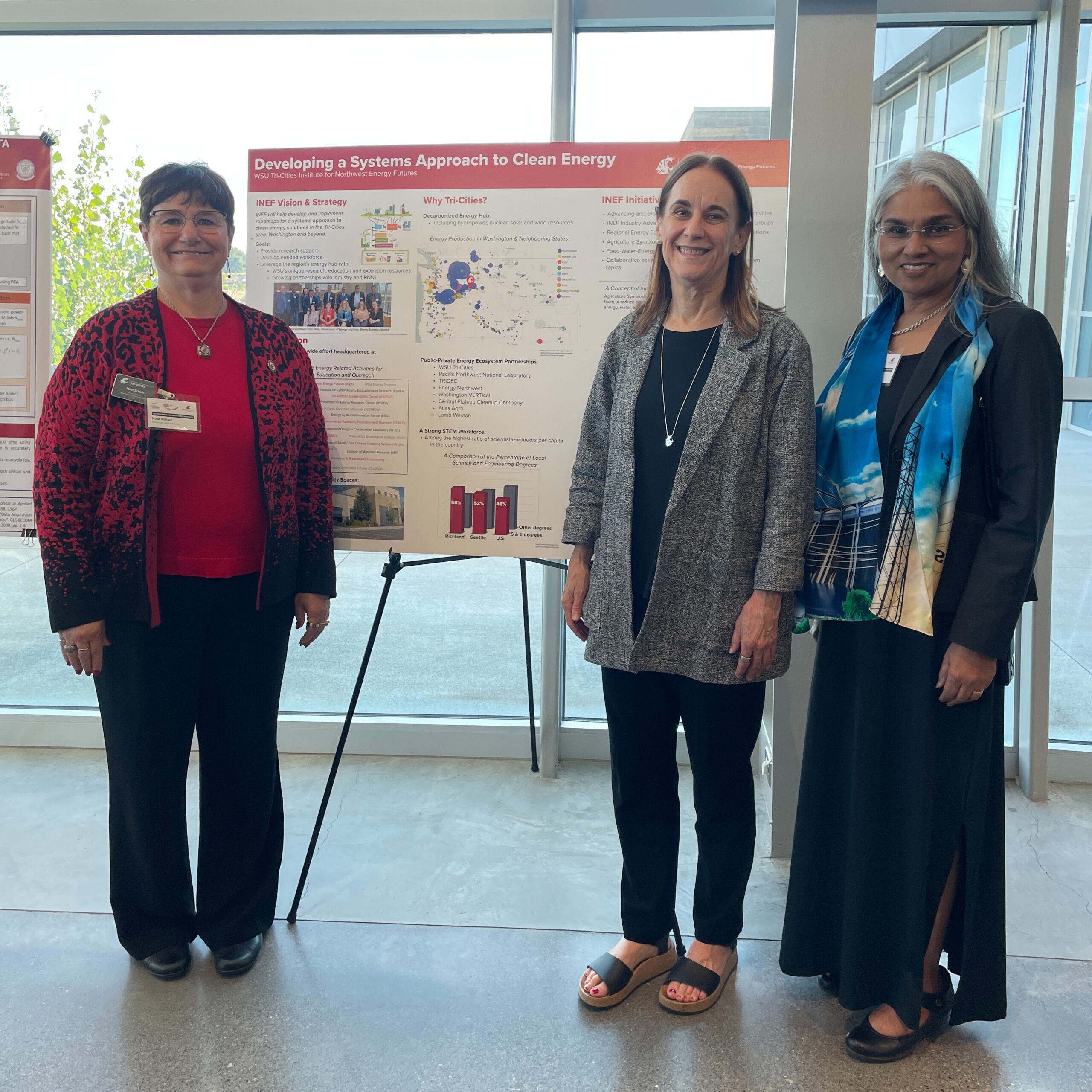 Noel Schulz, Chancellor Sandra Haynes, and Uzma Saddiqi stand in front of the INEF poster. 