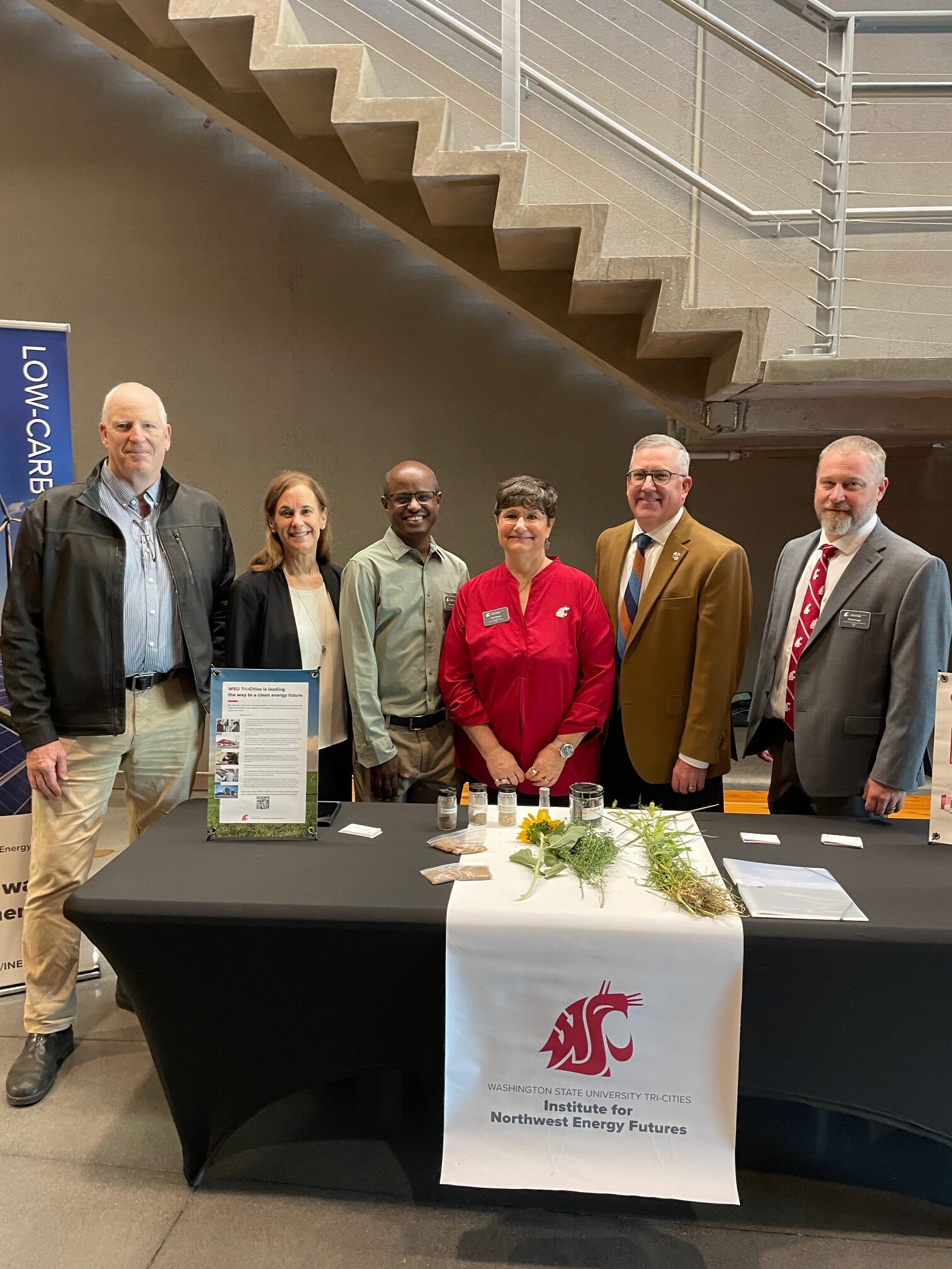 Washington State University Leadership standing in front of a table with plant matter. 