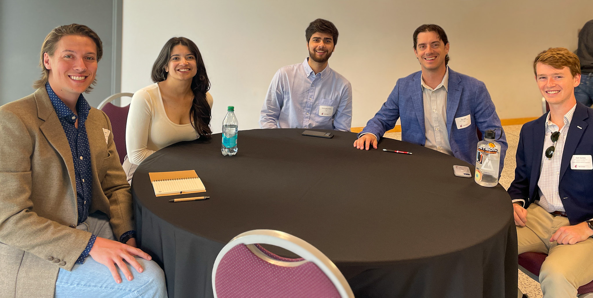 Participants sitting at a table and smiling. 