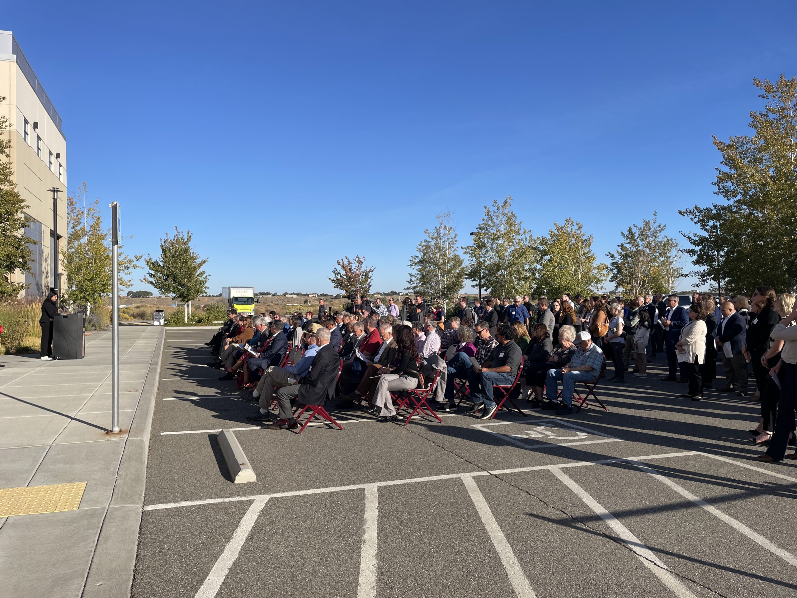 People sitting and watching the ribbon-cutting ceremony.
