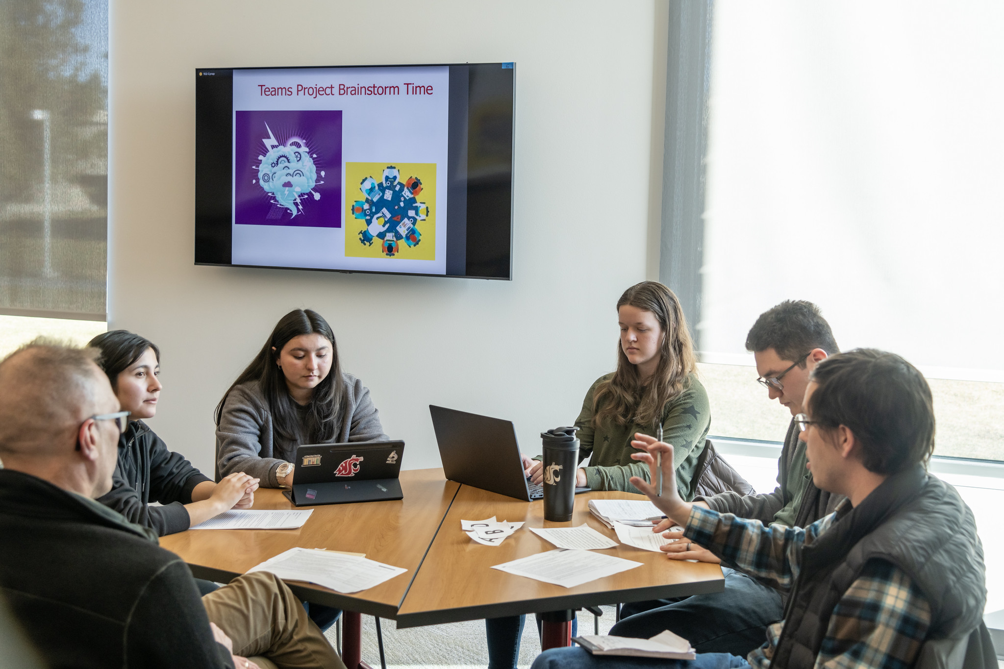 Students and mentors seated around a table brainstorming a project.