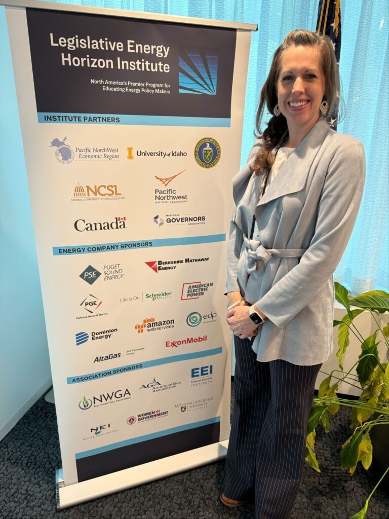 INEF Assistant Director Jillian Cadwell standing next to a banner at the Legislative Energy Horizon Institute