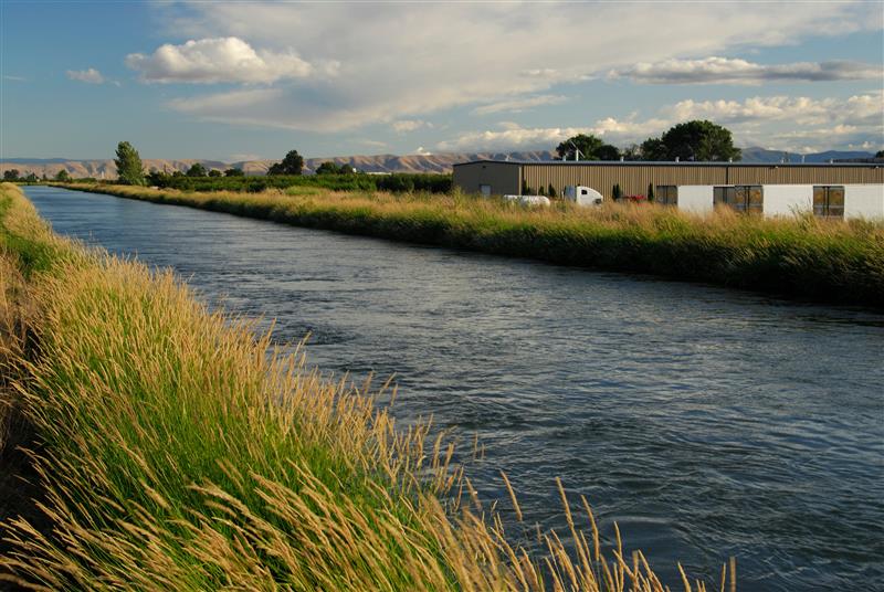 irrigation canal with light industrial building in the background.