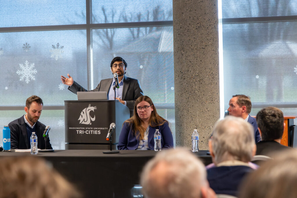 Guest speakers at a table in front of a seated audience.