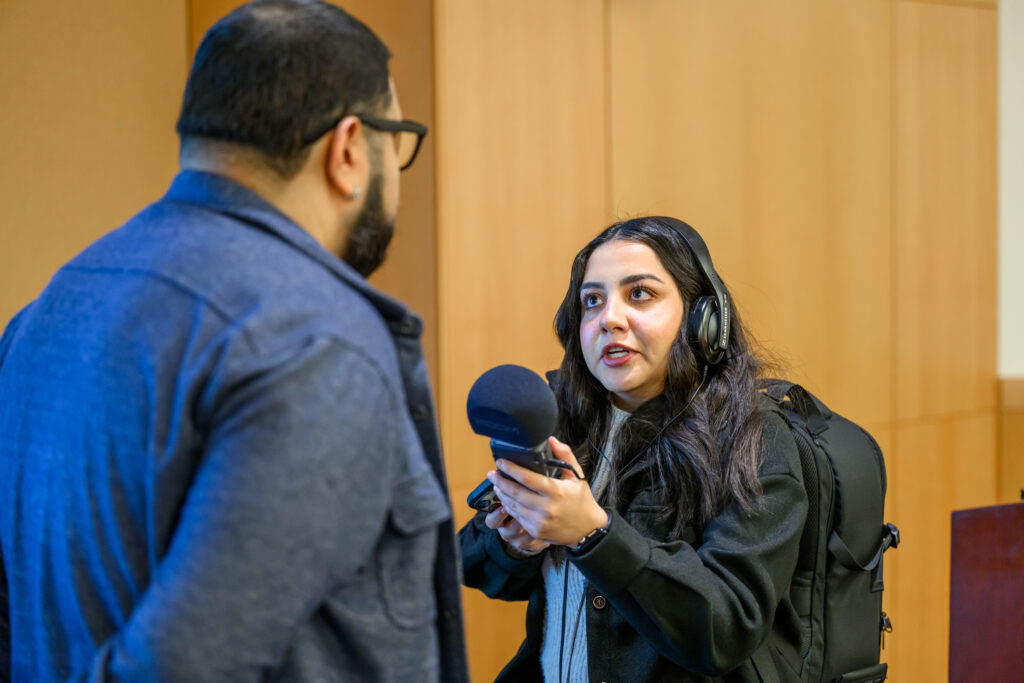 Monica Carrillo-Casas, Murrow Fellow, holding a microphone while interviewing a person.