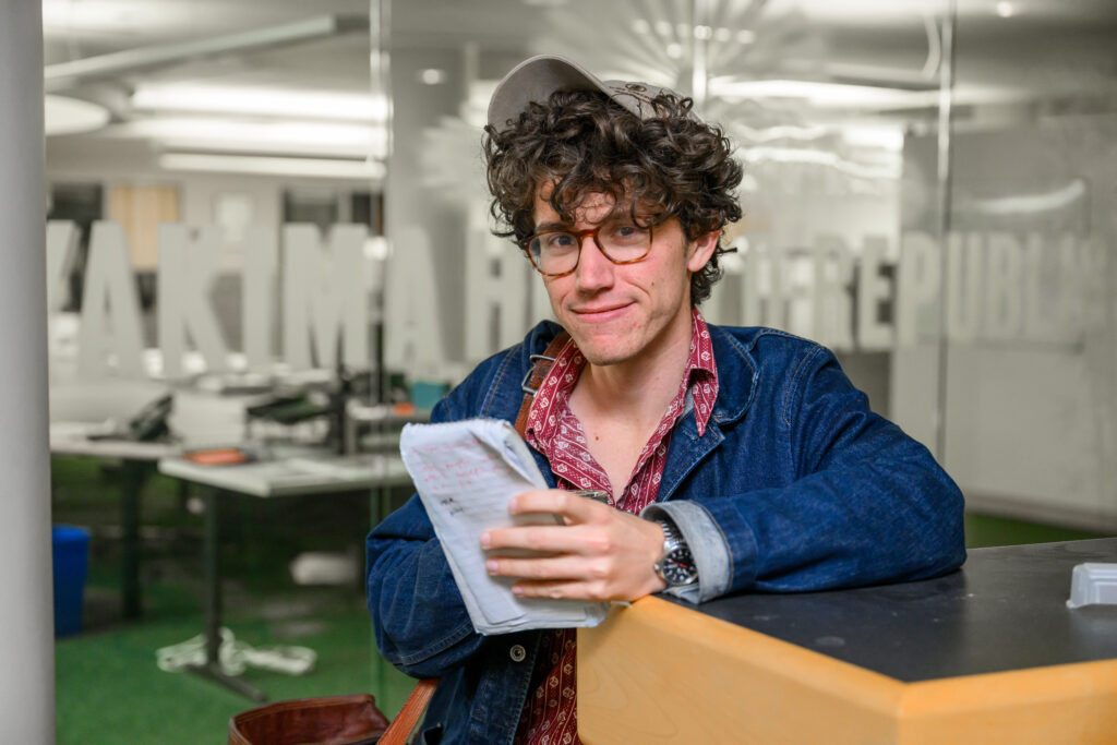 Queston Inghram, Murrow Fellow, holding a well-used notebook.