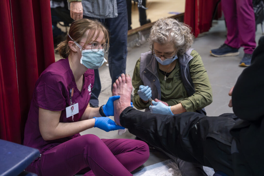 Nursing student caring for a person's foot while working with Range Student Health at WSU Spokane for a Hands and Feet Care clinic.
