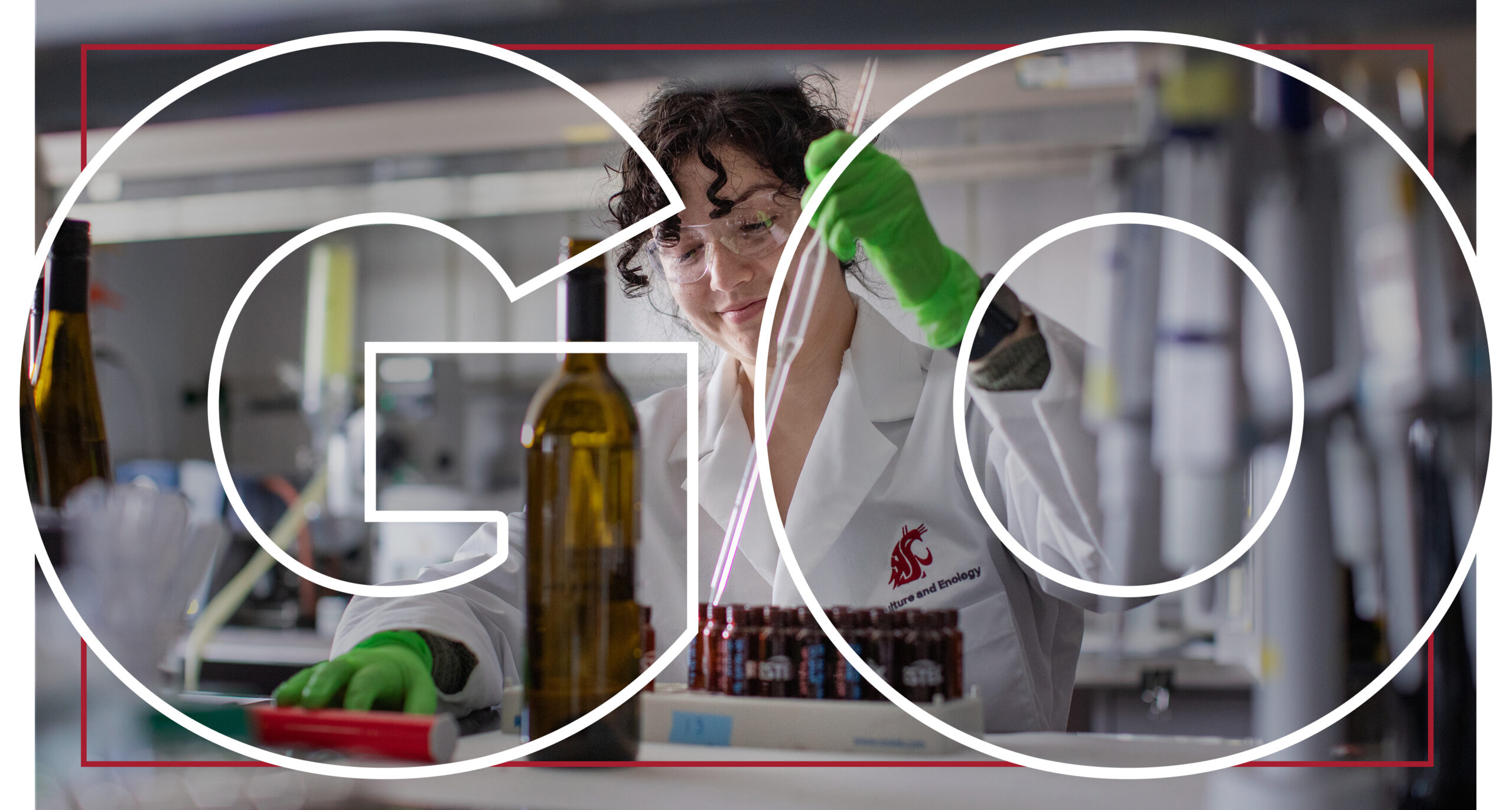 Large text reading Go overlaying a smiling researcher in safety glasses and a white lab coat using a tool to fill small bottles with a wine bottle in the foreground.