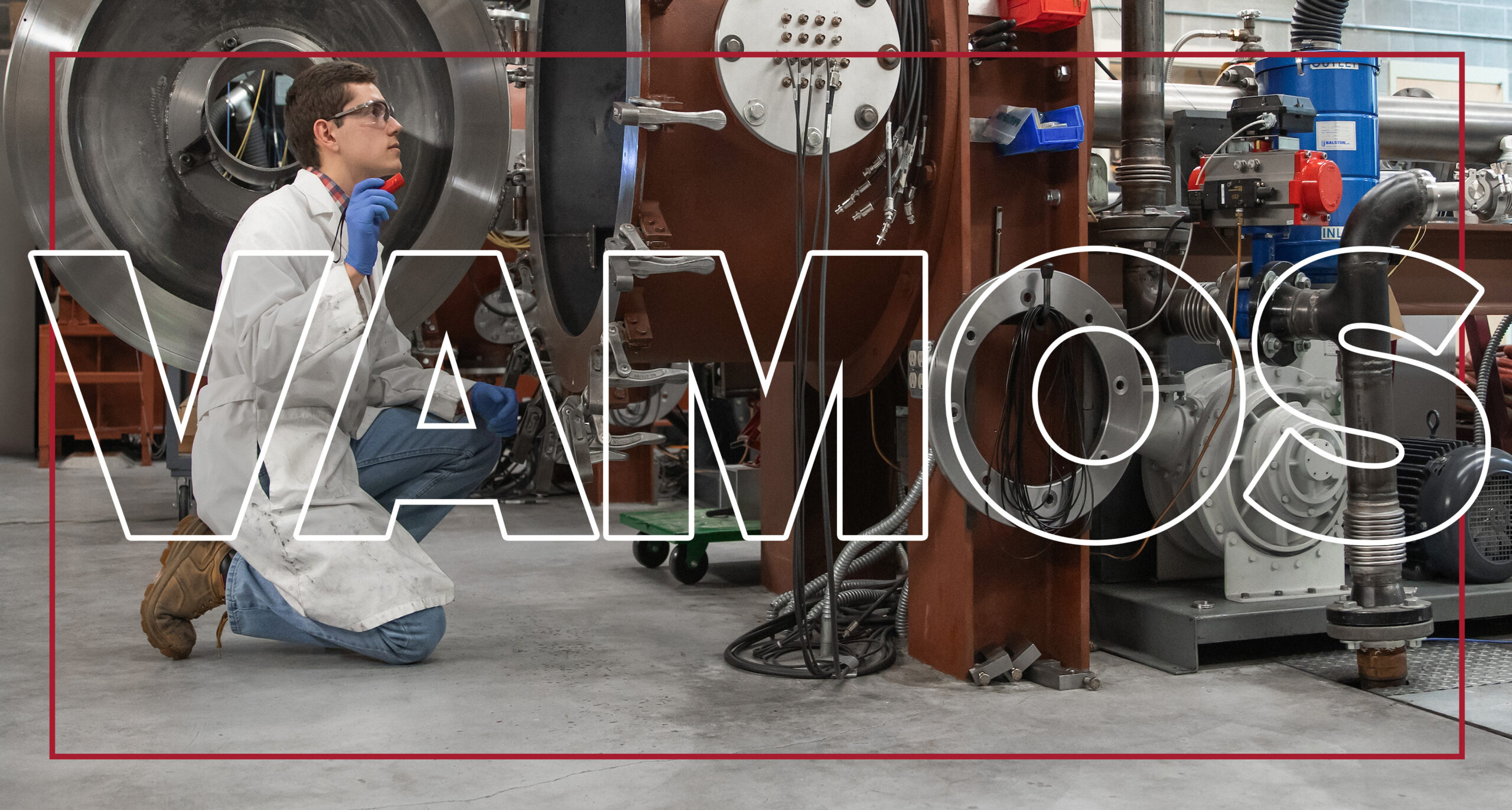 Texto grande “Vamos” superpuesto a una persona con gafas de seguridad, una bata de trabajo blanca y botas de trabajo marrones, arrodillada para mirar dentro de un gran dispositivo mecánico Abierto.