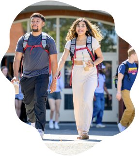 Two smiling students walking on campus.