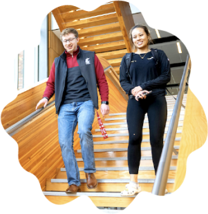 Two people walking down a flight of wooden stairs.