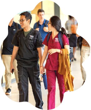 Two students walking in medical scrubs.