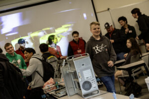 Students working on technical components or a computer tower chassis in a lab