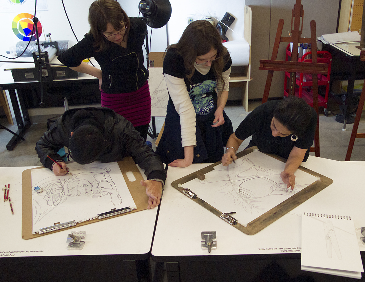Four students working on large sketchpads in a WSU Vancouver art studio, with two drawing and two observing.