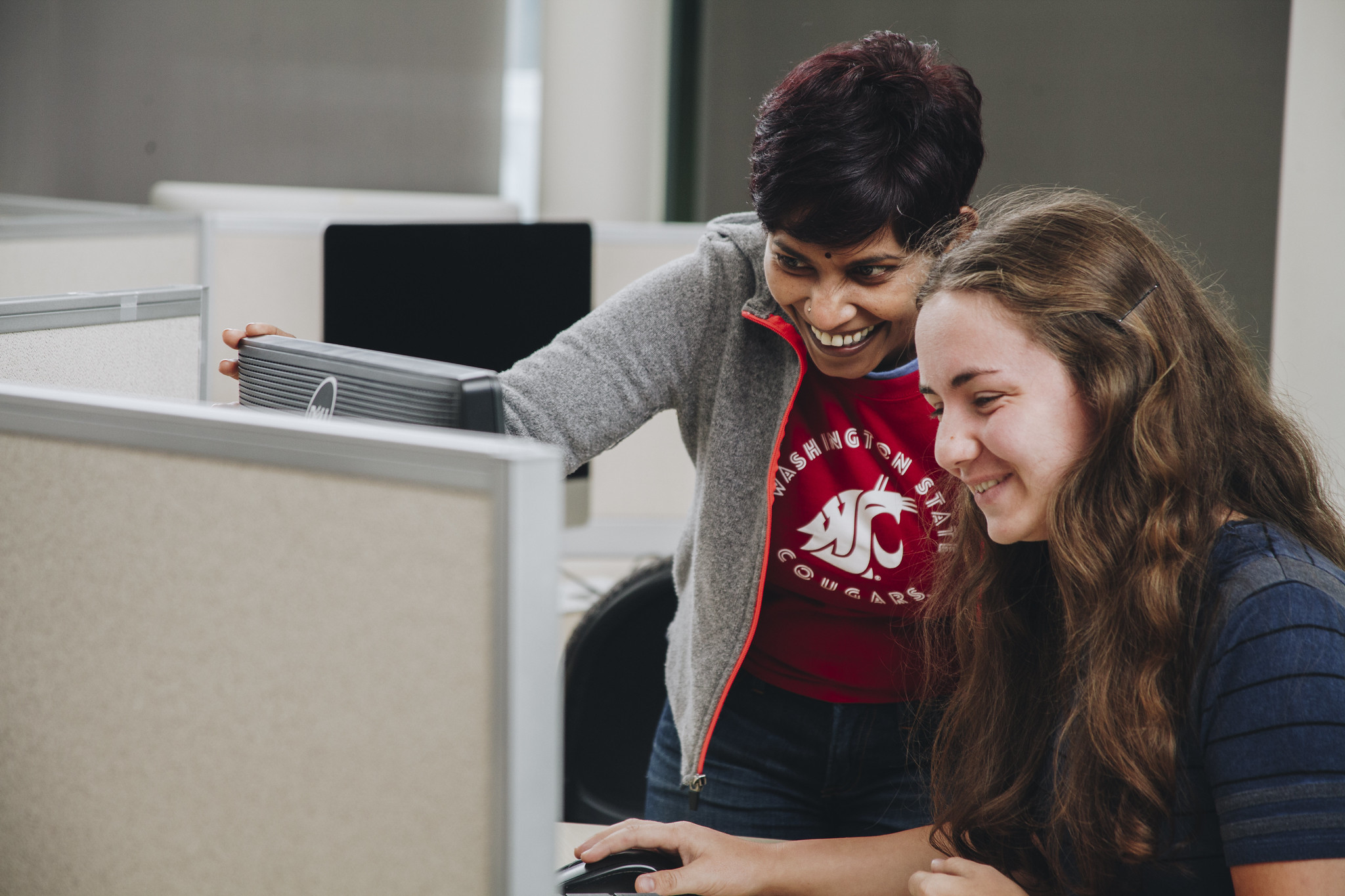 WSU Vancouver-Writing Placement Assessment | Two students discussing coursework while looking closely at a laptop screen indoors