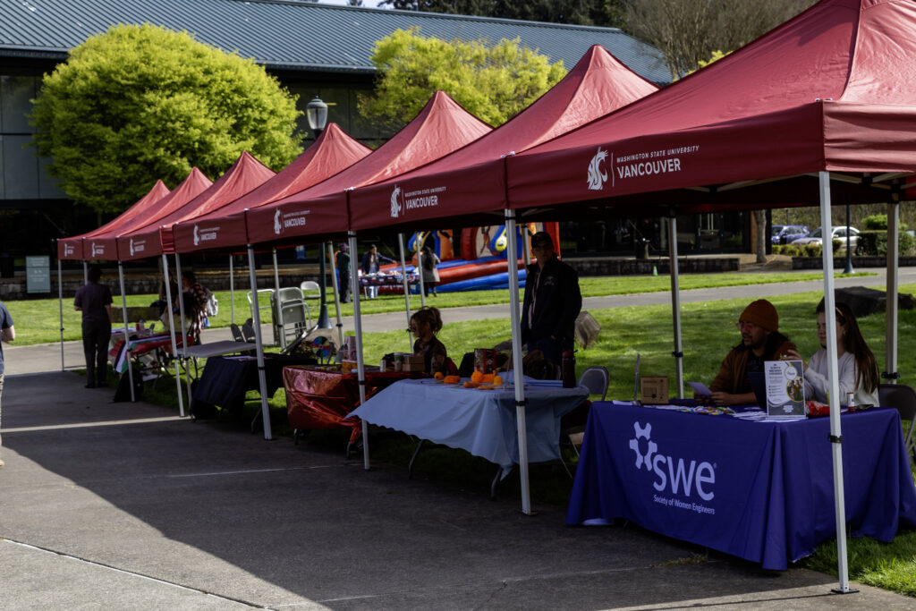 Red WSU Vancouver promotional pop-up tents set up along a campus walkway for an event