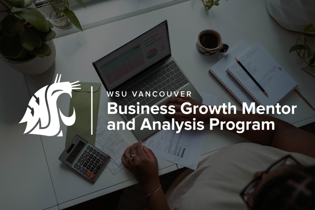 A laptop, calculator, and coffee mug arranged on a desk for the WSU Vancouver Business Growth Map program