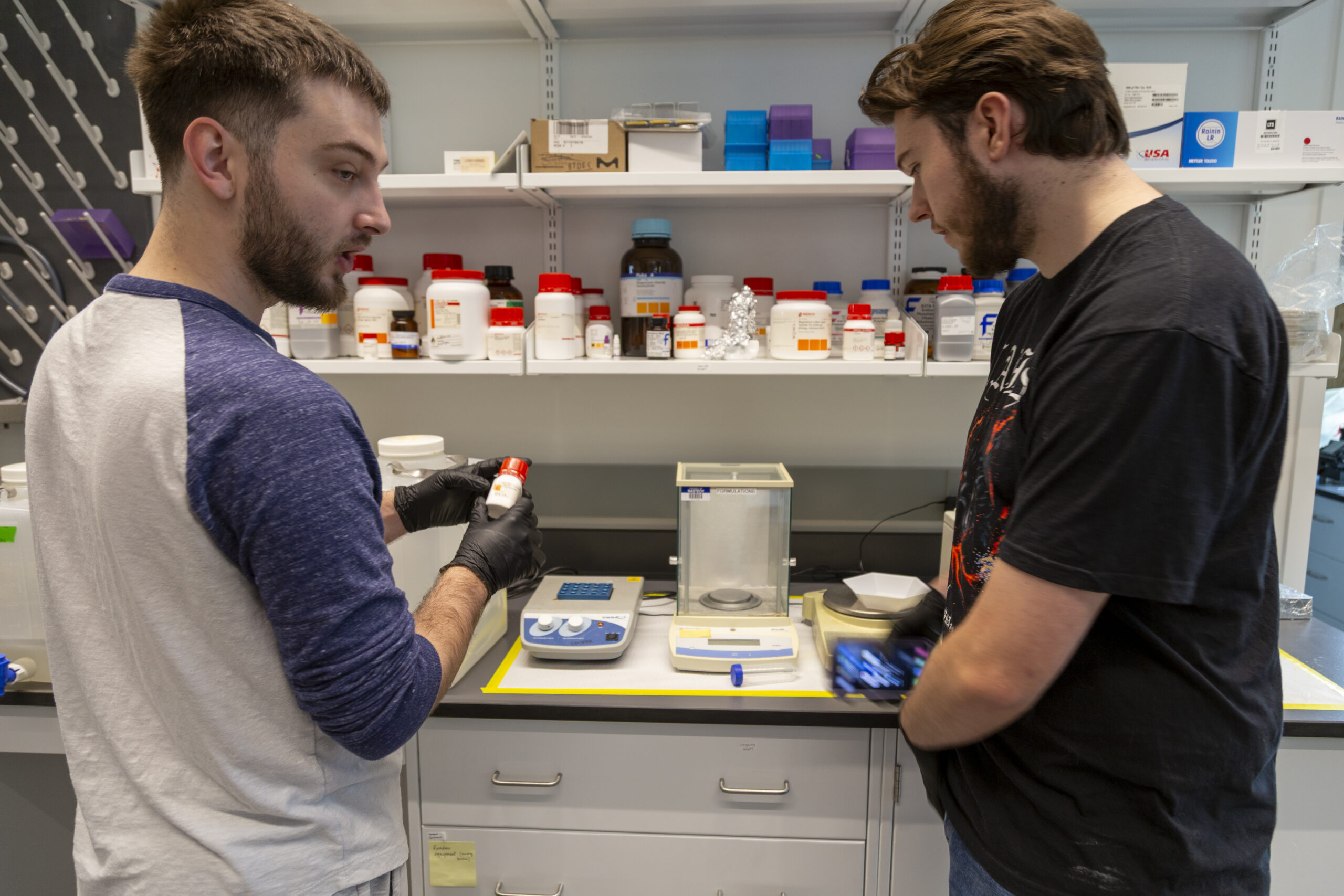 Two students preparing fluid measurements inside a WSU Vancouver chemistry research lab