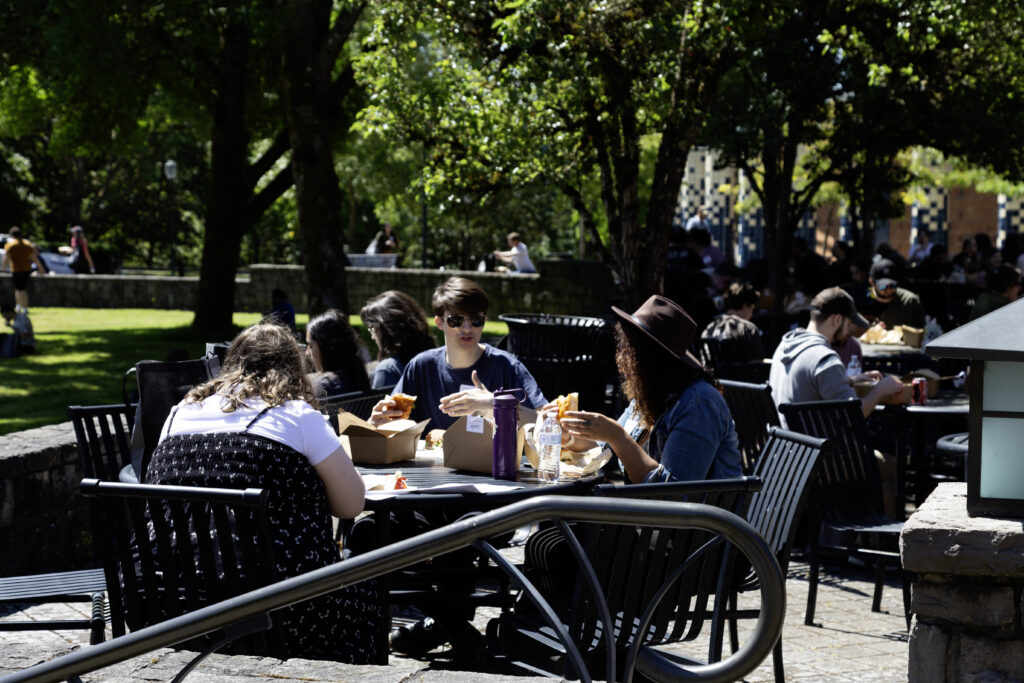 Students and faculty sitting at tables outdoors during a WSU Vancouver campus social mixer