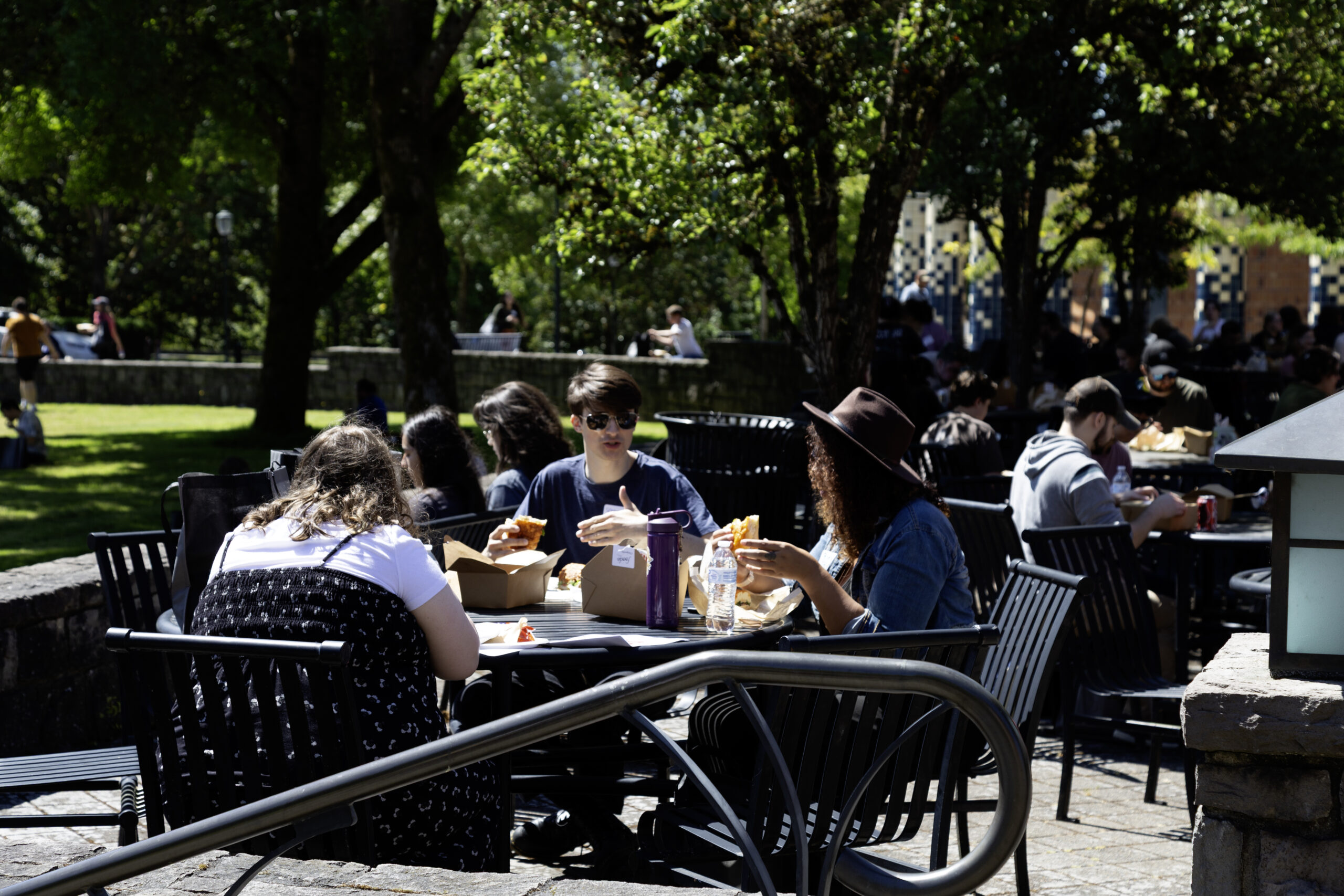 Students and faculty sitting at tables outdoors during a WSU Vancouver campus social mixer