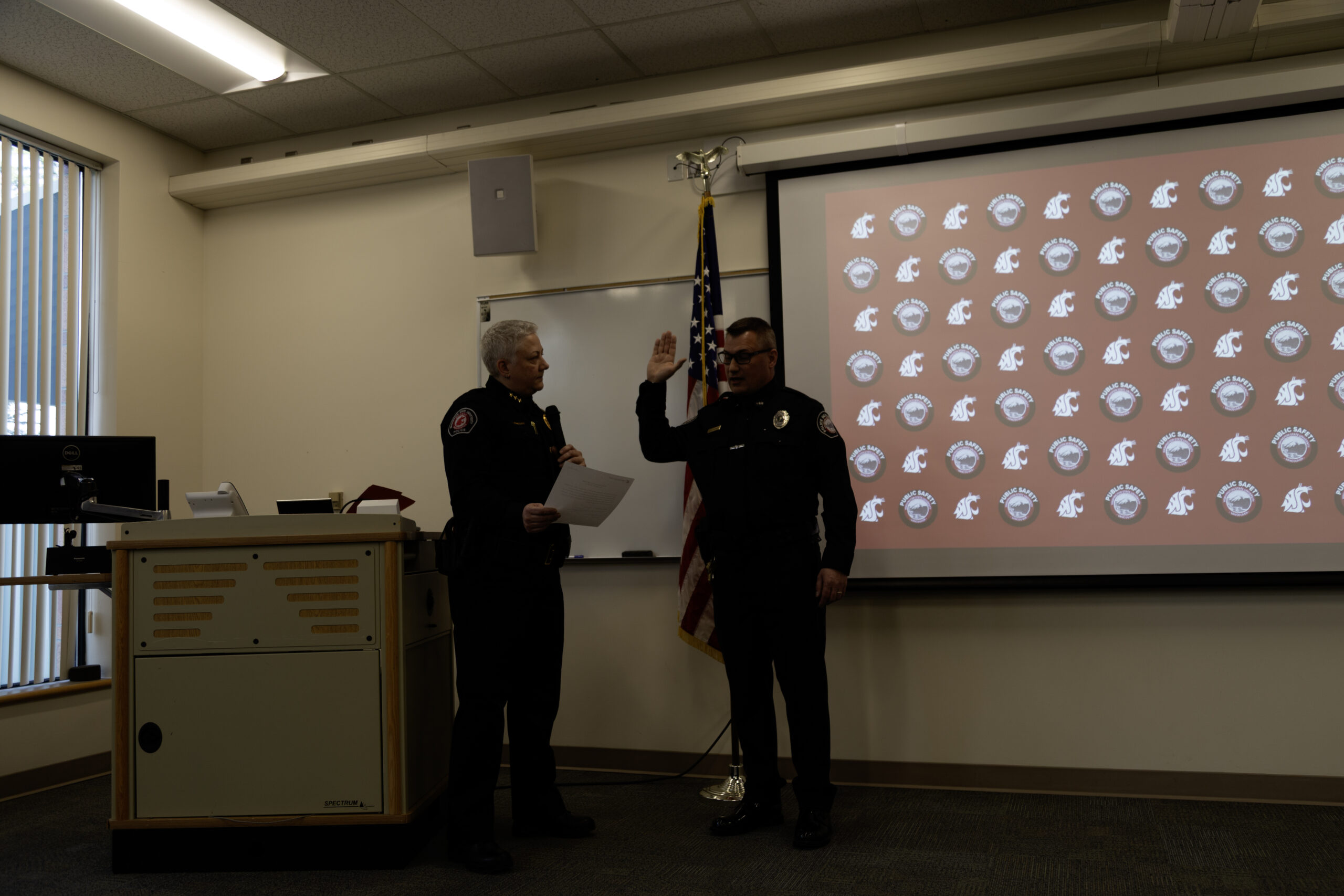 Two uniformed security or police officials taking an oath inside a WSU Vancouver presentation room