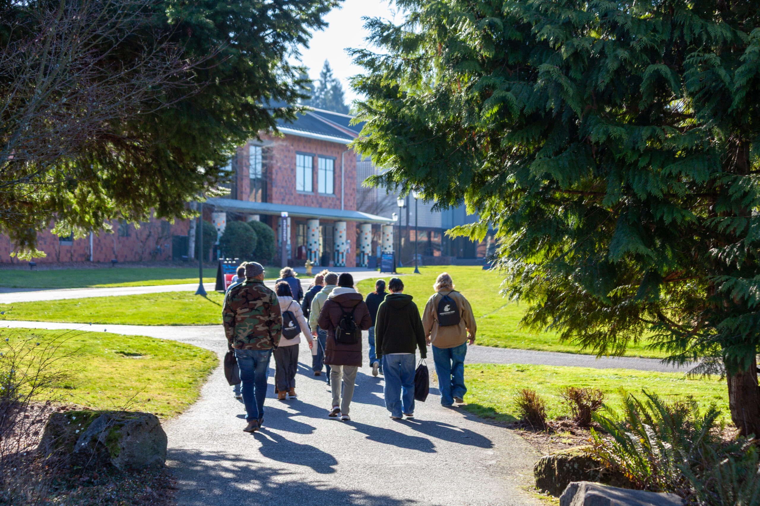 A long-distance view of students walking down a central campus path past brick academic buildings